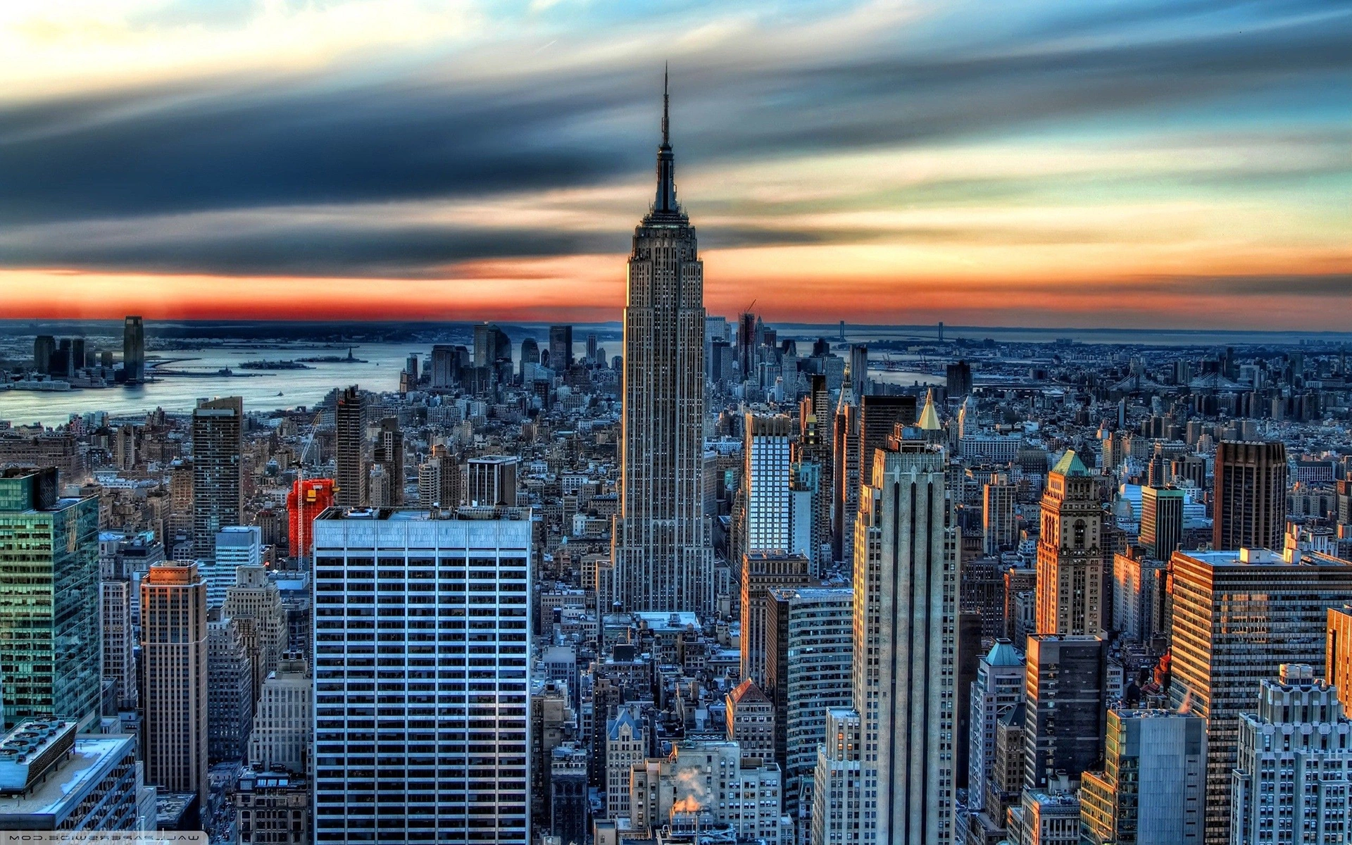 Empire State Building in New York City at sunset, with skyline and river in the background
